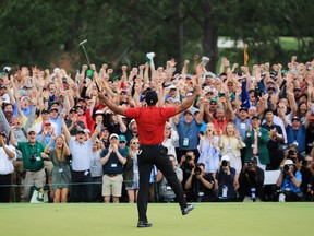Patrons cheer as Tiger Woods of the United States celebrates after sinking his putt on the 18th green to win during the final round of the Masters at Augusta National Golf Club on April 14, 2019 in Augusta, Georgia.