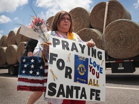 Lucy Gonzales carries a sign to be placed at a memorial outside of  Santa Fe High School on May 19, 2018 in Santa Fe, Texas. Yesterday morning, 17-year-old student Dimitrios Pagourtzis entered the school with a shotgun and a pistol and opened fire, killing 10 people.