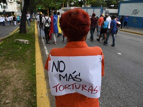 A woman with a sign reading "No more torture" on her back, takes part in an anti-government march in Caracas on July 5, 2019, during the anniversary of the Venezuelan Independence.