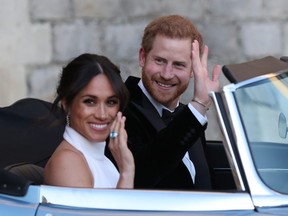 The Duchess of Sussex and Prince Harry, Duke of Sussex, wave as they leave Windsor Castle after their wedding to attend an evening reception at Frogmore House, hosted by the Prince of Wales on May 19, 2018 in Windsor, England.