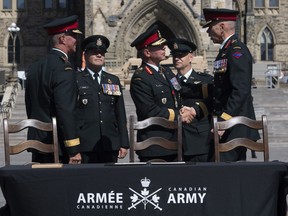 Chief of Defence Staff Jonathan Vance shakes hands with Lieutenant-General Wayne Eyre as he assumes command of the Canadian Army from Lieutenant-General Jean-Marc Lanthier (left) as Chief Warrant Officer Alain Gumond (second from left) and CWO Stuart Hartnell look during a change of command parade on Parliament Hill Tuesday, August 20, 2019 in Ottawa.