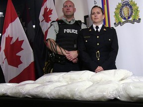 RCMP Cpl. Jon Cormier and RCMP Insp. Charlene O'Neill stand over seized methamphetamine from a truck at a Canada-U.S. border crossing in southern Alberta during a press conference in Calgary on Thursday, August 1, 2019.