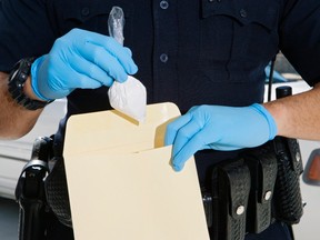 A police officer drops a bag of cocaine into an envelope.