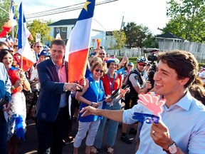 Prime Minister Justin Trudeau points to Conservative Leader Andrew Scheer while walking with the crowd during the Tintamarre in celebration of the National Acadian Day and World Acadian Congress in Dieppe, N.B., on Aug. 15, 2019.