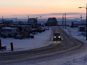 The sun rises as a car drives along a road in Iqaluit, Nunavut on Wednesday, December 10, 2014. Work is expected to begin on the first road into the heart of Canada's mineral-rich tundra after two funding announcements this week by federal transportation minister Marc Garneau.