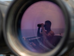 A U.S sailor uses binoculars to scan the ocean during a bridge watch aboard the guided-missile destroyer USS Bainbridge (DDG 96) in the Gulf, in this undated handout picture released by U.S. Navy on August 3, 2019.