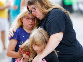 Mourners embrace Aug. 6, 2019, after taking flowers to a makeshift memorial for the slain and injured of the mass shooting that occurred two days prior in Dayton, Ohio.