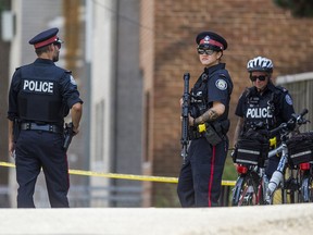 Toronto Police officers stand guard after two men were wounded by gunfire and a car was riddled with bullets at an apartment complex on Rochefort Drive in Toronto's Flemingdon Park on Aug. 7, 2019.