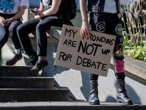 A student holds a sign that reads, 'my pronouns are not up for debate' at the University of Toronto. A U.S. study has found that gender minority students are four times more susceptible to mental health risks than other students.