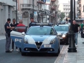 Police in Italy escort an accused mobster after his arrest in a probe revealing close ties between the Mafia in Canada and Italy.