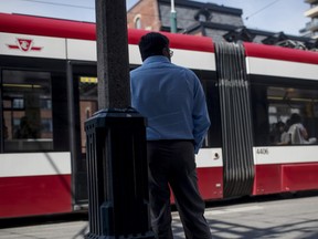 A man stands in front of a passing Toronto Transit Commission (TTC) streetcar in Toronto, Ontario, Canada, on Thursday, Aug. 2, 2018.