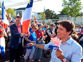 Prime Minister Justin Trudeau points to Conservative Leader Andrew Scheer while walking with the crowd during the Tintamarre in celebration of the National Acadian Day and World Acadian Congress in Dieppe, N.B., on Aug. 15, 2019.