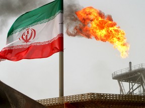 A gas flare on an oil production platform in the Soroush oil fields is seen alongside an Iranian flag in the Gulf July 25, 2005.