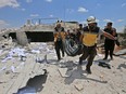 Members of the Syrian Civil Defence, also known as the "White Helmets", carry away in a blanket the body of a victim following a reported air strike on a makeshift clinic in the area of Tallmannis in Syria's northern Idlib province on August 21, 2019.