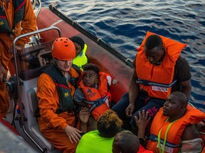 Handout picture taken on July 31, 2019 by German migrant rescue NGO Sea-Eye, shows members of the German migrant rescue charity NGO Sea-Eye transporting people from an overloaded rubber boat spotted in international waters off the Libyan coast to bring them to their vessel "Alan Kurdi".