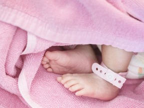 Closeup foot of baby with newborn ankle tag on bed in hospital textured background