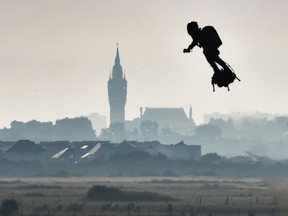 Franky Zapata on his jet-powered "flyboard" flies past the belfry of the city hall of Calais (C) after he took off from Sangatte, northern France, on August 4, 2019, during his attempt to fly across the 35-kilometre (22-mile) Channel crossing in 20 minutes, while keeping an average speed of 140 kilometres an hour (87 mph) at a height of 15-20 metres (50-65 feet) above the sea.