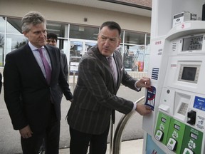 Ontario Environment Minister Rod Phillips, left, and provincial Energy Minister Greg Rickford display an anti-carbon tax sticker at a Toronto gas station on April 8, 2019.