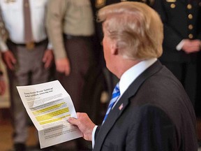 US President Donald Trump reads from an article praising his administration in response to an anonymous "senior official" who wrote an op-ed article entitled "I Am Part of the Resistance Inside the Trump Administration" in The New York Times on September 5.