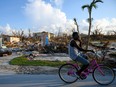 A man bikes past destroyed homes  in Marsh Harbour, Bahamas on September 10, 2019, one week after Hurricane Dorian.