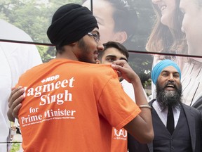 NDP leader Jagmeet Singh laughs as he reads the slogan on a volunteer's shirt while taking photos following an event in Brampton, Ont., Thursday, September 12, 2019.