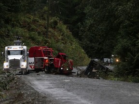 A tow-truck crew removes a bus from an embankment next to a logging road near Bamfield, B.C., on Saturday, Sept. 14, 2019.