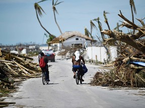 Residents pass damage caused by Hurricane Dorian on September 5, 2019, in Marsh Harbour, Great Abaco Island in the Bahamas.