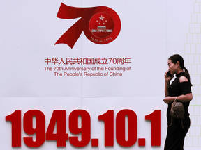 A woman walks past a billboard in Weifang with the founding date of People's Republic of China, ahead of the country's 70th anniversary.