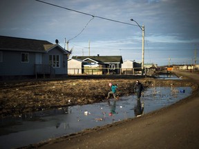 Indigenous children play in water-filled ditches in Attawapiskat, Ont. on April 19, 2016. The Canadian Human Rights Tribunal has awarded more than $2 billion in compensation to First Nations kids who were ripped away from their families by a chronically underfunded welfare system.THE CANADIAN PRESS/Nathan Denette