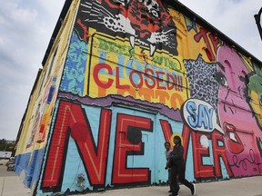 Pedestrians walk by a building near the Eastern Market in Detroit on Friday, September 13, 2019 that features art work by Windsor, ON. artist Daniel Bombardier, known as Denial in the art community. Mercedes-Benz USA is suing Bombardier and three other artists whose murals appeared in photographs the company posted on Instagram in 2018. The company claims the artists have threatened to sue for copyright infringement, and are seeking a judge's ruling asserting that the images do not constitute infringement.