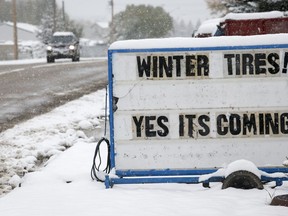 As sign outside a garage encourages drivers to put on snow tires and warning of winter appears a but late as winter weather descends on Cremona, Alta., Sunday, Sept. 29, 2019. Some areas of southern Alberta are expecting up to 60 centimetres of snow by Tuesday.