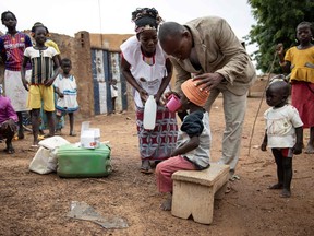 Community health workers give a child Seasonal malaria chemoprevention (SMC), in the village of Goundri, in Ziniare, north east of Burkina Faso's capital Ouagadougou on August 20, 2019.