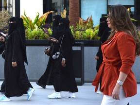 Saudi human resources professional Mashael al-Jaloud, 33, walks in western clothes past women wearing niqab, an Islamic dress-code for women, at a commercial area in the Saudi capital Riyadh on September 3, 2019.