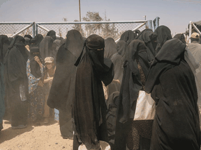 Women and children stand by a gate during a brief dust storm at the foreigners' section of al-Hol camp in Syria.