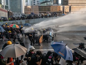 Pro-democracy protesters are hit by a water cannon during clashes at the Central Government Offices on September 15, 2019 in Hong Kong, China. Pro-democracy protesters have continued demonstrations across Hong Kong, calling for the city's Chief Executive Carrie Lam to immediately meet the rest of their demands, including an independent inquiry into police brutality, the retraction of the word 'riot' to describe the rallies, and genuine universal suffrage, as the territory faces a leadership crisis.