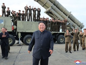 This picture taken on August 24, 2019 and released on August 25 by North Korea's official Korean Central News Agency (KCNA) shows North Korean leader Kim Jong Un (C) celebrating the test-firing of a 'newly developed super-large multiple rocket launcher' at an undisclosed location.