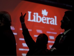 Liberal party supporters flash victory signs while watching the federal election results at the Palais des Congres in Montreal on Oct. 21, 2019.