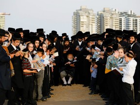 Ultra-Orthodox Jewish men surround their rabbi as they pray on a beach in the southern Israeli town of Ashdod, while performing the "Tashlich" ritual on October 7, 2019 during which "sins are cast into the water to the fish."