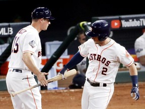 Alex Bregman #2 of the Houston Astros hands his bat to first base coach Don Kelly #15 after hitting a solo home run against the Washington Nationals during the first inning in Game Six of the 2019 World Series at Minute Maid Park on October 29, 2019 in Houston, Texas.