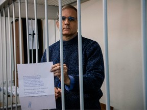 Paul Whelan, a former U.S. Marine accused of espionage and arrested in Russia in December 2018, holds a message as he stands inside a defendants' cage before a hearing to decide to extend his detention at the Lefortovo Court in Moscow on October 24, 2019.