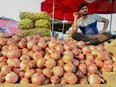 A vendor waits for customers to sell onions at a wholesale vegetable market on the outskirts of Amritsar on September 19, 2019.