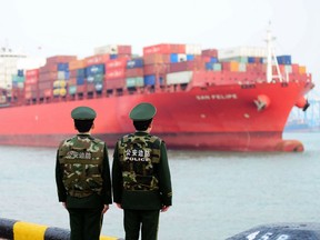 Chinese police officers watch a cargo ship at a port in Qingdao in China's eastern Shandong province on March 8, 2018.