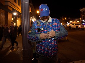 Conservative supporter Alexander Mosicki-Nystrom, wearing a Make Canada Great Again hat, adjusts his jacket covered in buttons for Conservative candidate Sam Lilly, in Edmonton on the night of the federal election, Oct. 21, 2019.
