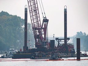 Spill response workers adjust a boom after a tugboat capsized and sank on the Fraser River between Vancouver and Richmond, B.C., on Tuesday August 14, 2018. The Transportation Safety Board says the capsizing of a tug at the mouth on the Fraser River in Vancouver shows the risks the industry faces because of a lack of awareness of the factors that led to the incident last summer.