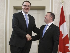 Alberta premier Jason Kenney shakes hands with Jason Nixon, Minister of Environment and Parks after being sworn into office,in Edmonton on Tuesday, April 30, 2019. Alberta has introduced a new climate plan for the province's big greenhouse gas emitters. Environment minister Jason Nixon says it will achieve what he calls similar emissions cuts to the old government's plan but at less cost to industry.