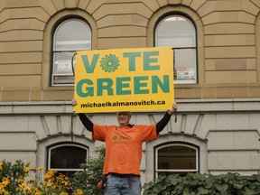 The Green Party candidate in the only riding in Alberta held by the NDP before the federal election call has dropped out of the race and is urging supporters to vote for his New Democrat rival. Green Party candidate Michael Kalmanovitch holds up his sign in front of "I love Canadian Oil and Gas" signs in the Legislature windows during the Climate Strike in Edmonton, Friday, Sept. 27, 2019.