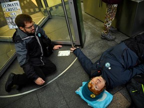 A protester lies on the ground after she glued herself to revolving door of Barclays Bank during an Extinction Rebellion demonstration in Canary Wharf, London, Britain October 14, 2019.