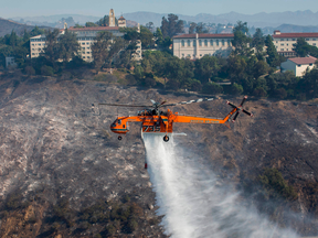 A helicopter drops water on houses as the Getty Fire burns in the Brentwood area, California on Oct. 28, 2019.