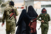 Kurdish guards escort women, reportedly wives of ISIL fighters, in the al-Hol camp in Syria, in July 2019.