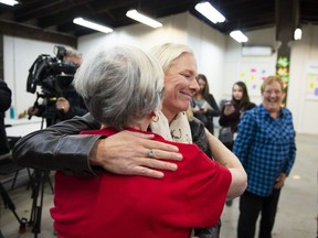 Re-elected Liberal MP Catherine McKenna hugs a member of her team after speaking to reporters after a misogynistic slur was spray painted on her image on the window, in Ottawa, on Thursday, Oct. 24, 2019.